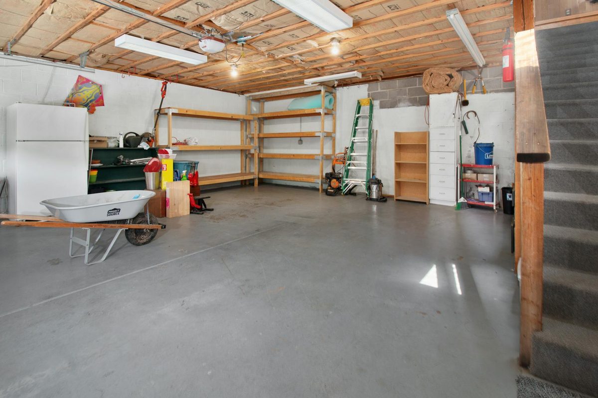 Home garage interior with a bare concrete floor and storage shelves